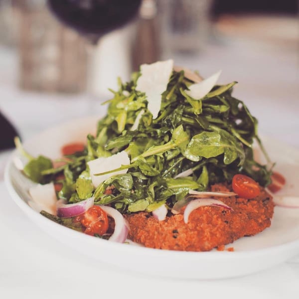 Viaggio's breaded chicken Milanese topped with arugula, cherry tomatoes, red onion, and parmesan cheese.